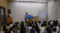 大型絵本の読み聞かせを聞く3年生